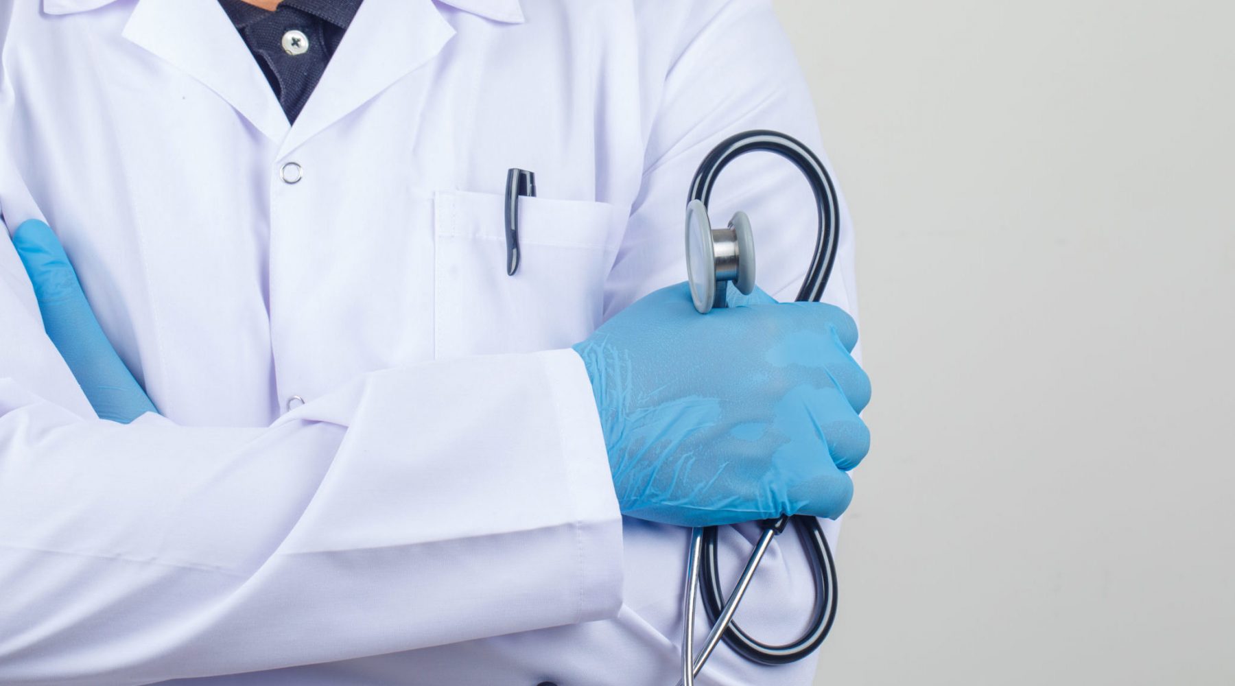Doctor crossing arms while holding stethoscope in white coat fro